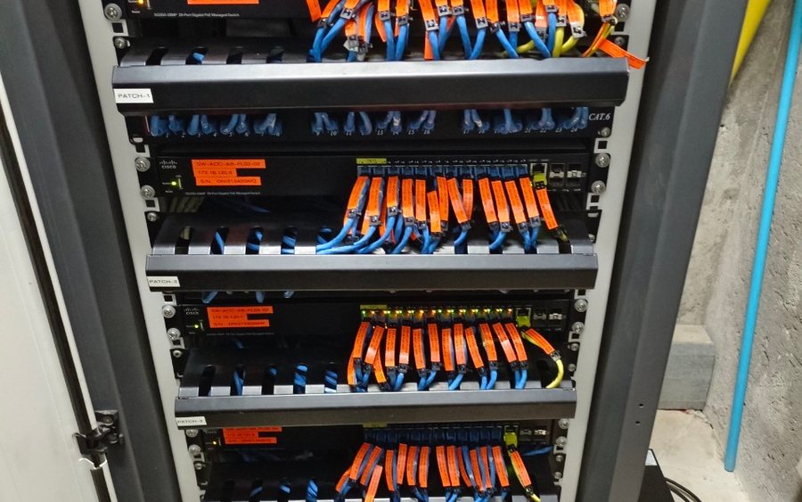 Network cabinet with patch panels and colour-coded orange and blue patch leads